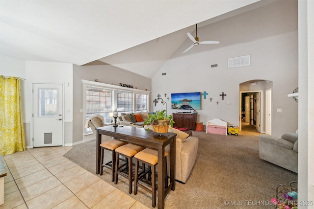 tiled dining area with ceiling fan and high vaulted ceiling