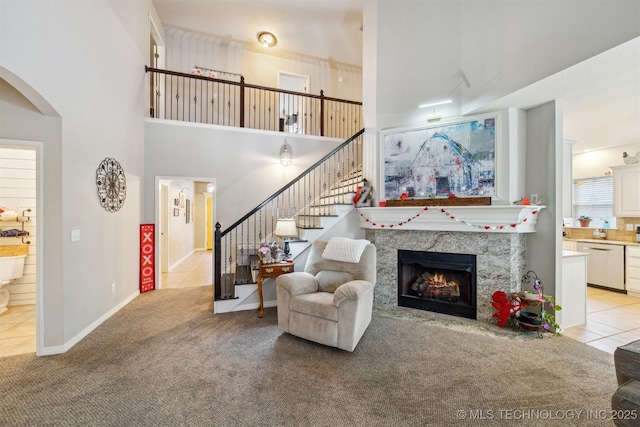 carpeted living room featuring a towering ceiling and a high end fireplace