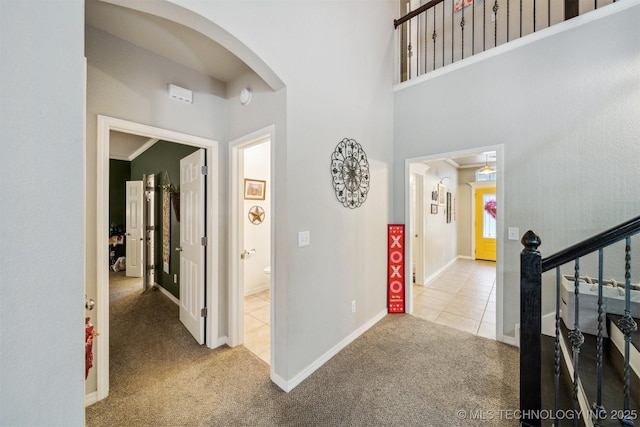 hall featuring crown molding, light colored carpet, and a high ceiling