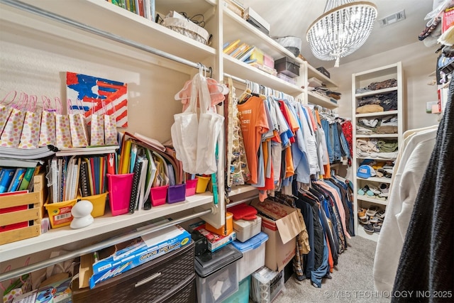 walk in closet with an inviting chandelier and carpet flooring