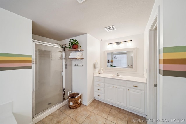 bathroom featuring a shower with door, vanity, tile patterned floors, and a textured ceiling