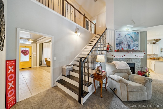 staircase featuring tile patterned flooring, a tile fireplace, and a towering ceiling