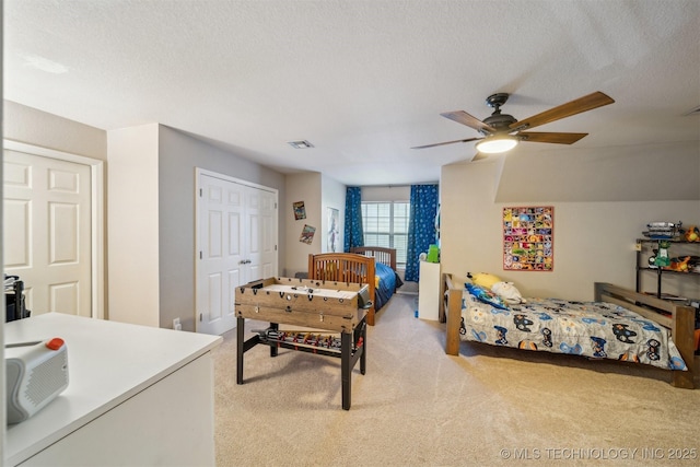 bedroom with ceiling fan, light carpet, and a textured ceiling