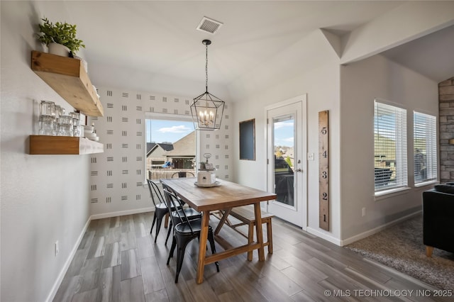 dining space featuring dark wood-type flooring and a notable chandelier