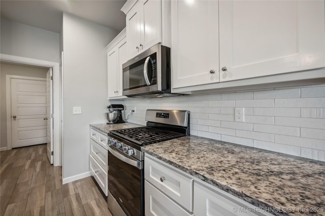 kitchen featuring light hardwood / wood-style flooring, white cabinetry, backsplash, stainless steel appliances, and light stone countertops