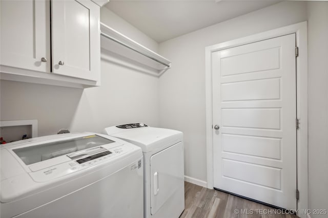 laundry area featuring cabinets, separate washer and dryer, and light hardwood / wood-style flooring