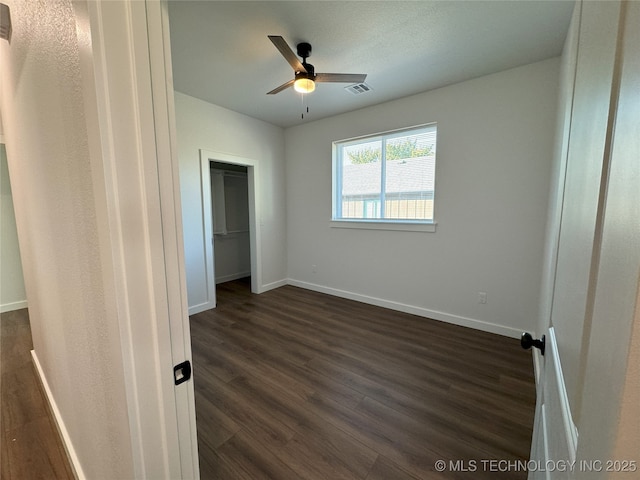 unfurnished bedroom featuring ceiling fan, a closet, and dark hardwood / wood-style flooring