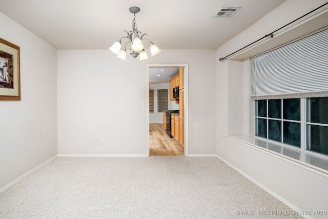 carpeted empty room featuring a notable chandelier