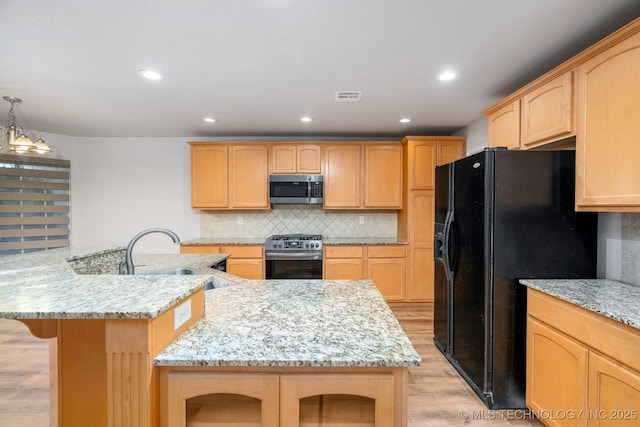 kitchen featuring light stone countertops, appliances with stainless steel finishes, sink, and a center island with sink