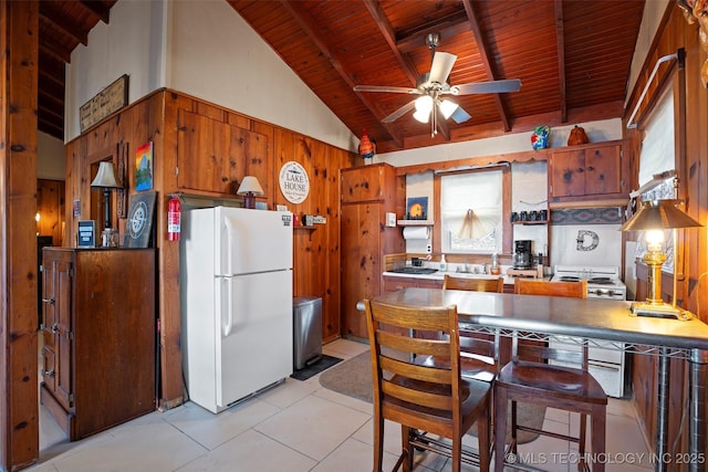 kitchen with wood walls, beamed ceiling, white fridge, ceiling fan, and wood ceiling