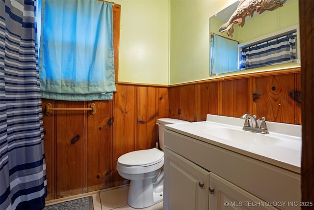 bathroom with vanity, wooden walls, and toilet