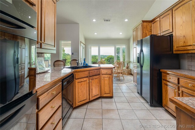 8775 Leonard St, Kingston, OK 73439 - kitchen with tasteful backsplash, sink, light tile patterned floors, black appliances, and a textured ceiling