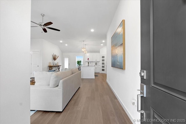 living room featuring vaulted ceiling, ceiling fan, and light wood-type flooring