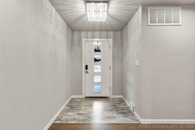 doorway with light hardwood / wood-style flooring and a chandelier