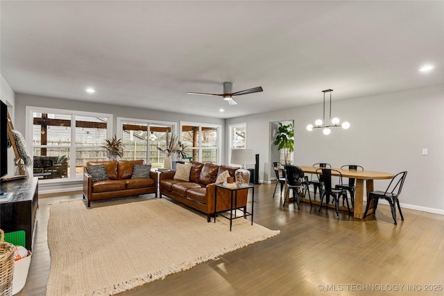 living room featuring hardwood / wood-style floors, ceiling fan with notable chandelier, and a healthy amount of sunlight