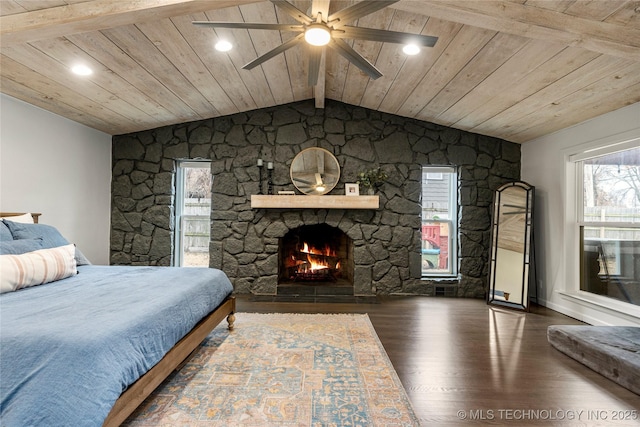 bedroom with dark hardwood / wood-style flooring, wood ceiling, a stone fireplace, and lofted ceiling with beams