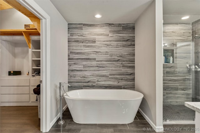 bathroom featuring plus walk in shower and tile walls