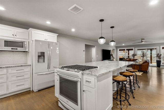 kitchen with white appliances, dark wood-type flooring, and white cabinets