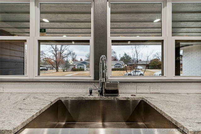 interior details featuring sink and light stone countertops