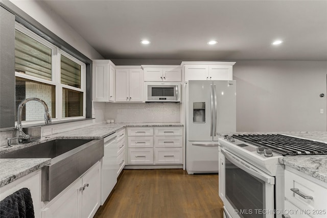 kitchen featuring dark hardwood / wood-style floors, white cabinetry, sink, light stone countertops, and white appliances