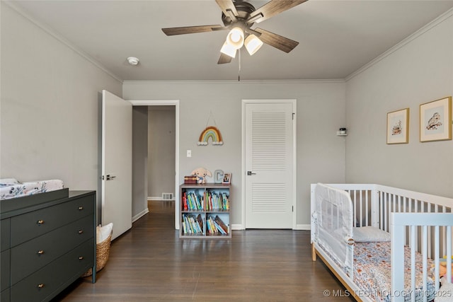 bedroom with a nursery area, ceiling fan, ornamental molding, and dark hardwood / wood-style floors