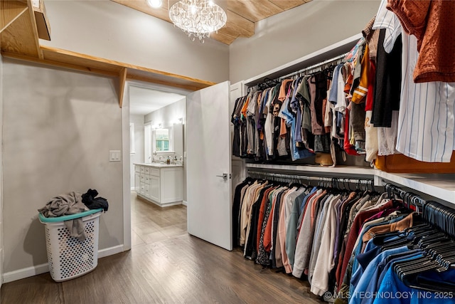 walk in closet with dark hardwood / wood-style flooring and a chandelier