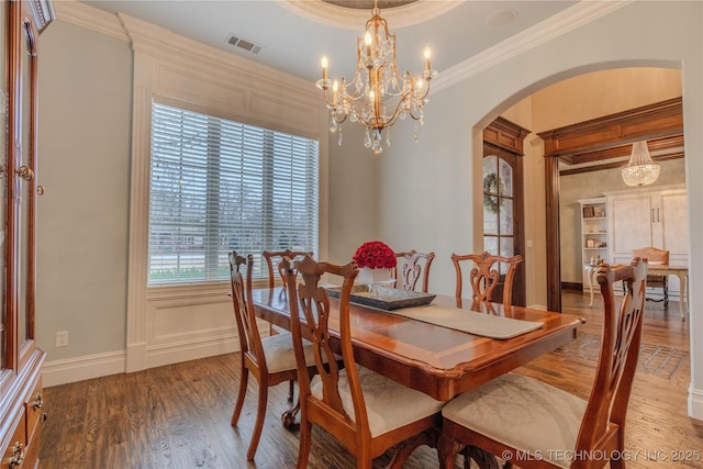 dining room featuring crown molding, a tray ceiling, a chandelier, and hardwood / wood-style floors