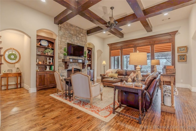 living room featuring hardwood / wood-style flooring, ceiling fan, beam ceiling, coffered ceiling, and a fireplace