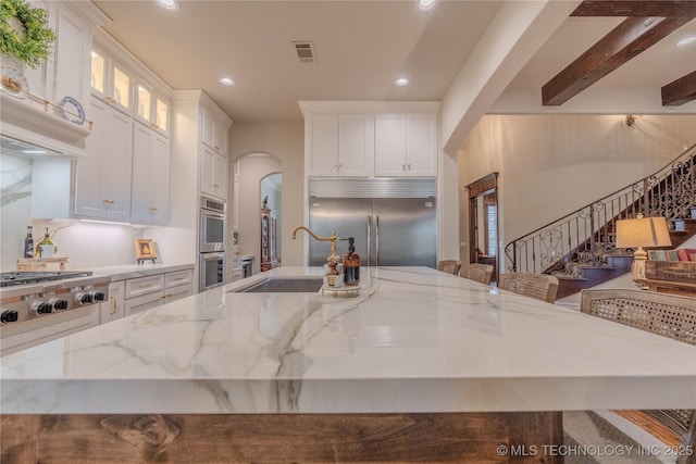 kitchen featuring appliances with stainless steel finishes, sink, a breakfast bar area, white cabinets, and light stone countertops