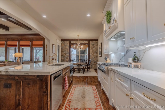 kitchen featuring sink, white cabinetry, light stone counters, appliances with stainless steel finishes, and a kitchen island with sink