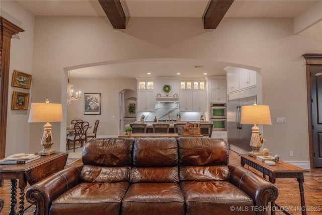 living room with wood-type flooring, beam ceiling, and a chandelier