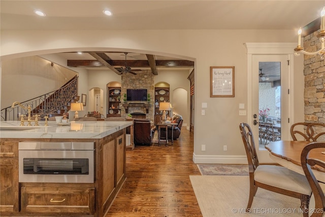 kitchen featuring sink, dark wood-type flooring, ceiling fan, a fireplace, and oven