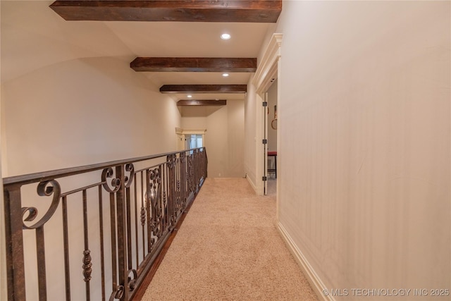 corridor featuring beamed ceiling and light colored carpet