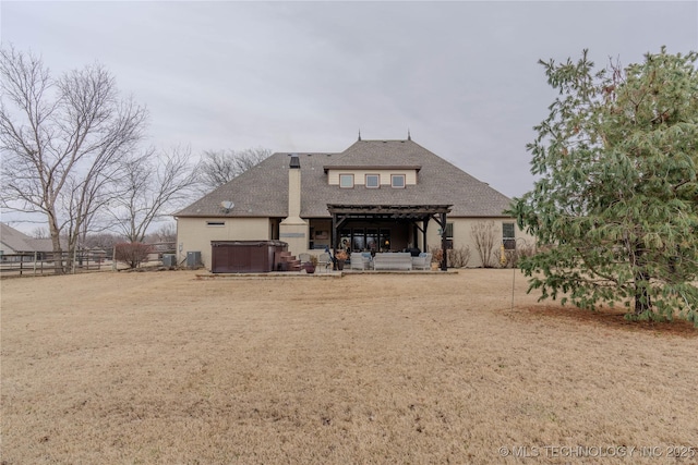 rear view of property featuring a hot tub, a pergola, and a patio