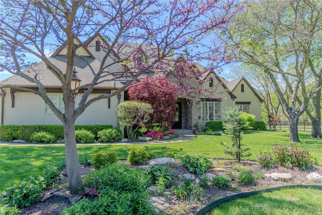 view of front of property featuring brick siding, fence, and a front lawn