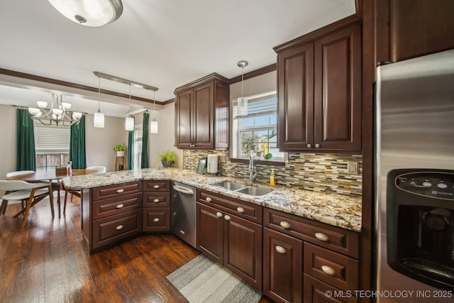 kitchen with appliances with stainless steel finishes, tasteful backsplash, sink, hanging light fixtures, and kitchen peninsula