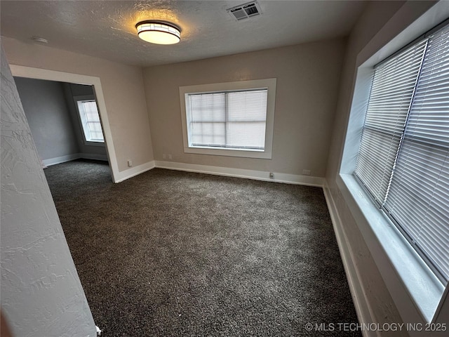 empty room with a textured ceiling and dark colored carpet