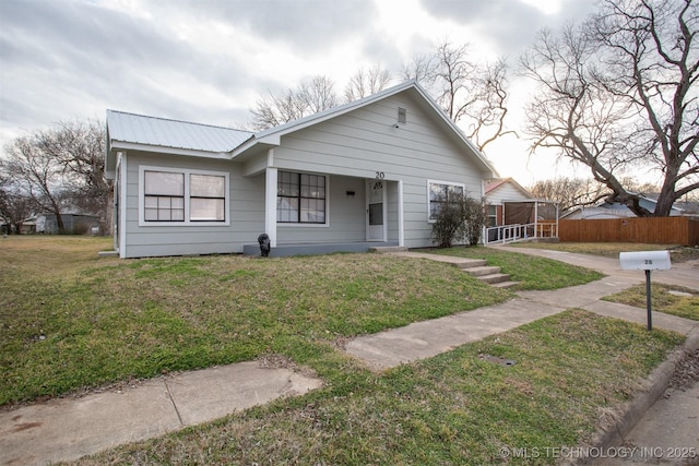 bungalow with a front yard, metal roof, and fence