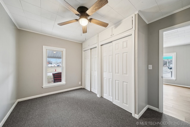 unfurnished bedroom with ornamental molding, two closets, and dark carpet