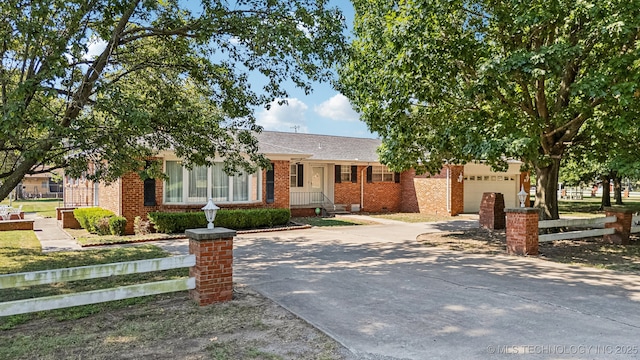 view of front of house featuring an attached garage, fence, concrete driveway, and brick siding