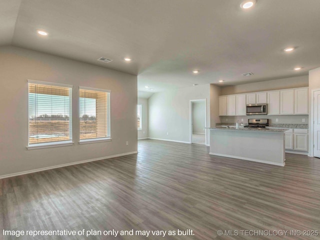 unfurnished living room with lofted ceiling, a healthy amount of sunlight, and dark hardwood / wood-style floors