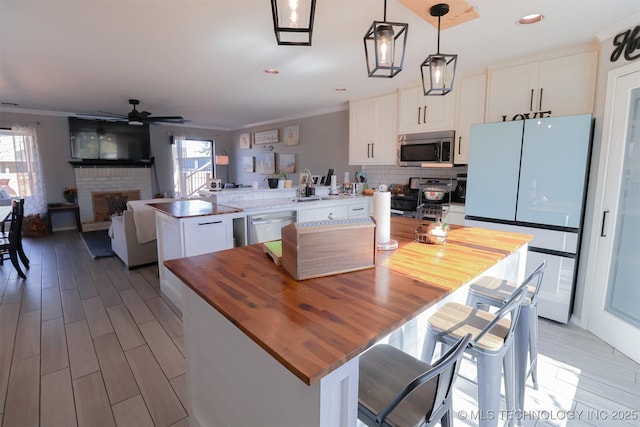 kitchen featuring appliances with stainless steel finishes, pendant lighting, white cabinets, kitchen peninsula, and a healthy amount of sunlight