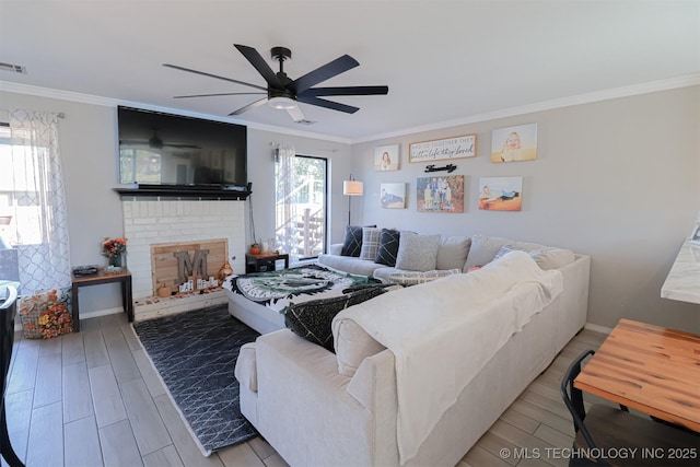 living room featuring crown molding, a brick fireplace, hardwood / wood-style floors, and ceiling fan