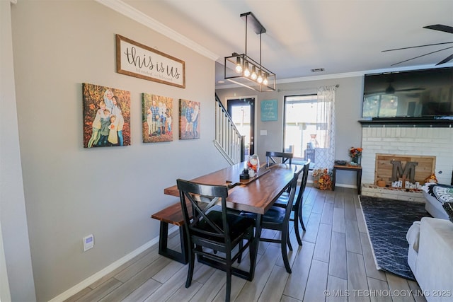 dining area featuring a fireplace, ornamental molding, and ceiling fan