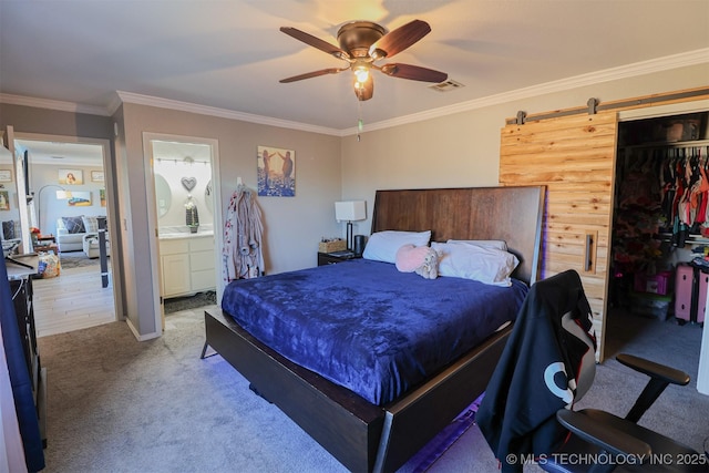 bedroom featuring crown molding, a barn door, carpet flooring, and a closet