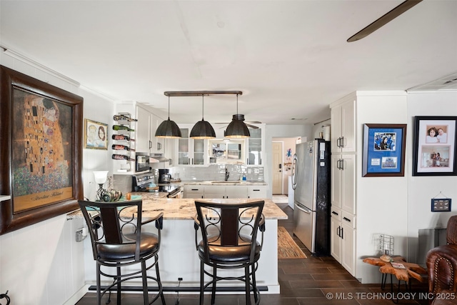 kitchen featuring decorative light fixtures, white cabinetry, sink, kitchen peninsula, and stainless steel appliances