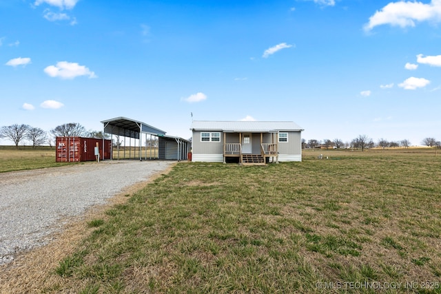 manufactured / mobile home featuring a carport, a porch, a front yard, and a rural view