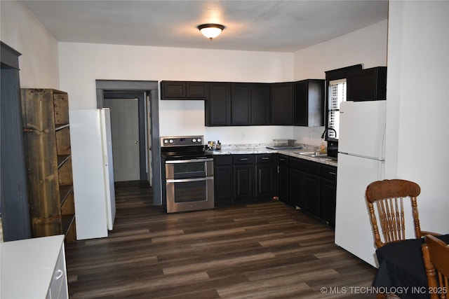 kitchen featuring dark wood-type flooring, range with two ovens, sink, and white fridge