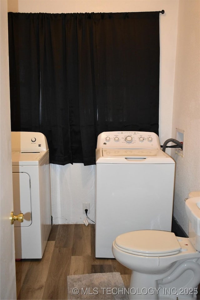 bathroom featuring separate washer and dryer, wood-type flooring, and toilet