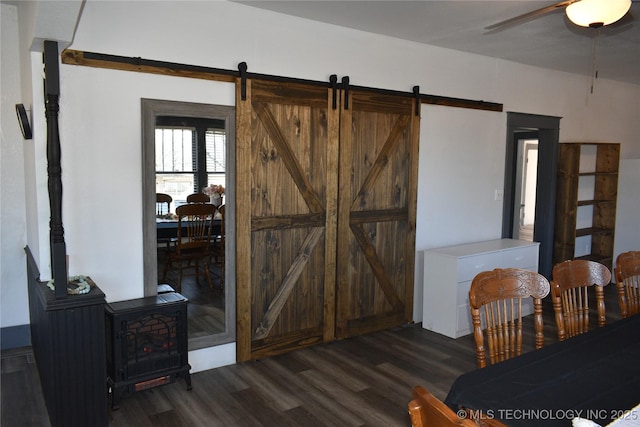 dining space featuring dark hardwood / wood-style flooring, a barn door, and ceiling fan